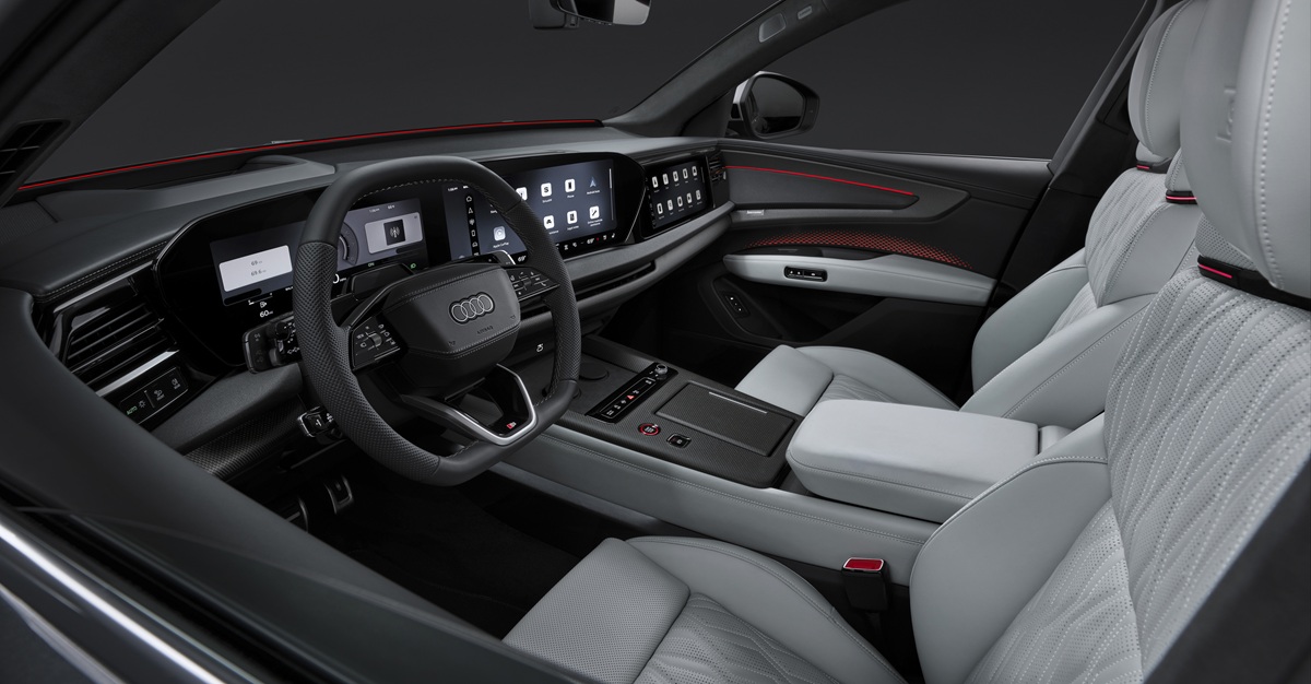 Interieur van de nieuwe Audi Q9 met breed multischerm dashboard, lichtgrijs leder en rode sfeerverlichting