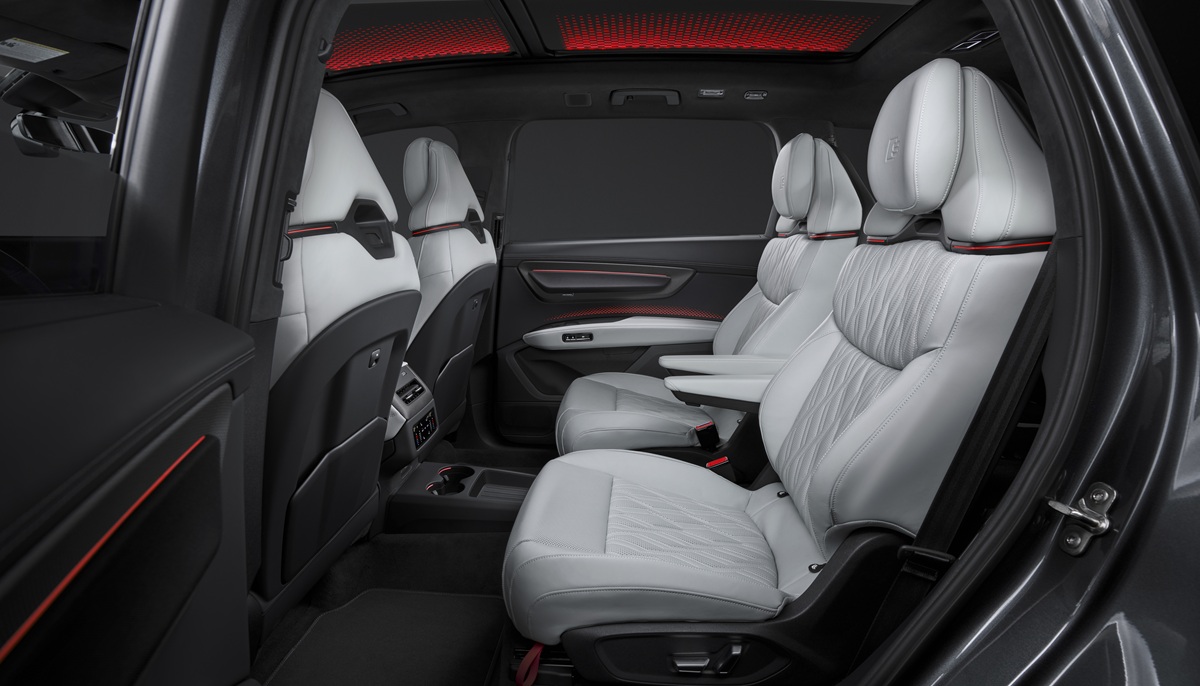 Ruime achterbank van de nieuwe Audi Q9 met lichtgrijze leren stoelen, rode sfeerverlichting in het panoramadak en drie zitplaatsen