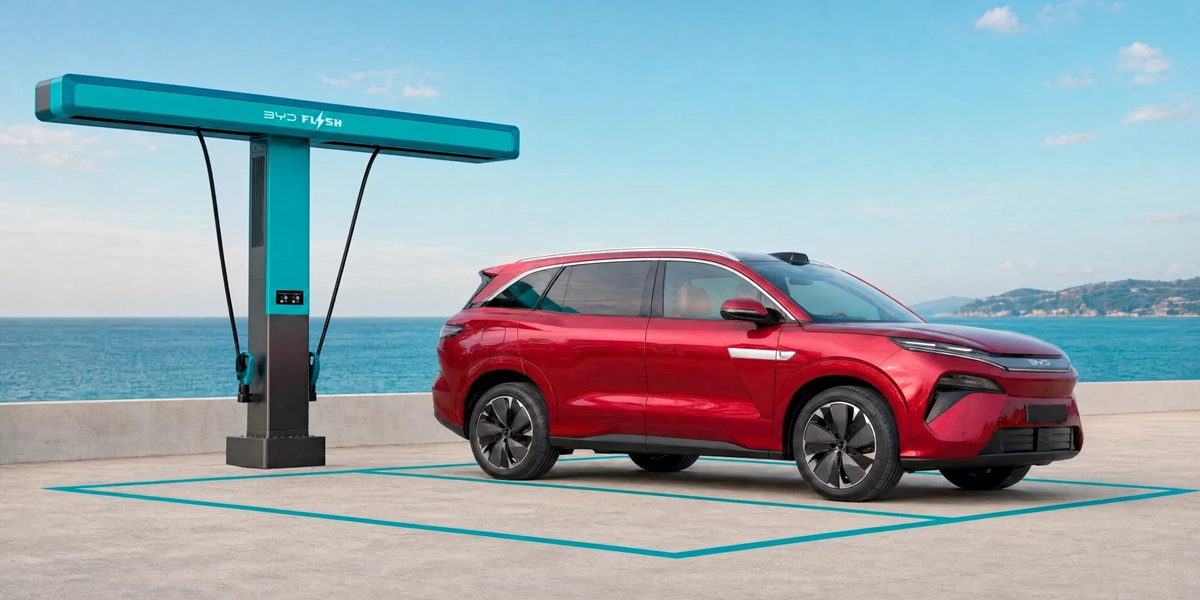 BYD Atto 8 met revolutionaire Flash Charging-technologie Rode BYD Atto 8 naast een turquoise BYD Flash Charging-snellaadstation aan zee